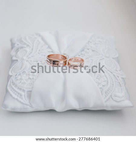Wedding rings with diamonds on a white silk pillow with laces. Wedding theme