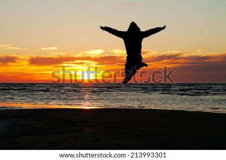 happy man jump on a beach at sunset