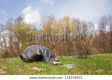Garbage in plastic bag dump in woods lying on fresh grass in early spring season, Clean Up the World gathering in Poland. Earth Day and nature dispose, horizontal orientation, nobody.
