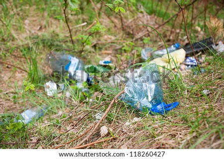 Illegal scatter garbage in blue plastic bag dump in woods lying on fresh grass in early spring season, Clean Up the World gathering in Poland. Earth Day and nature dispose, horizontal orientation.