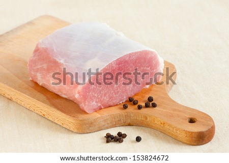 Raw pork meat for cutlets polish kotlet schabowy, fresh portion of meat and grains of pepper lying on board ready to prepare cuisine. Nobody, horizontal orientation.