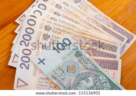 Many two and one hundred polish zloty banknotes lying on wooden table detail, objects in horizontal orientation, nobody.