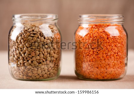 Red and green lentils seeds in glass jars, plenty healthy raw grains in studio shot, horizontal orientation, nobody.
