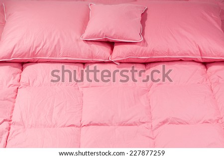 Cotton pink fluffy three pillows on big duvet without cover, eiderdown filled with fluff or feathers. Horizontal orientation, nobody.