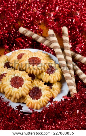 Jelly cookies pile in red Christmas chains. Delicious jelly decorated cookies in vertical orientation, objects lying, studio shot, view from above.
