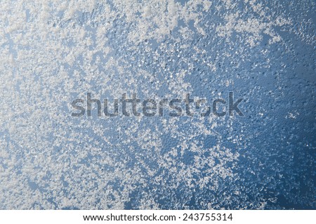 Snow and water condensation texture on window glass, transparent glass in winter and ice with white snow in contact with morning warm sunlight. Horizontal orientation, nobody.