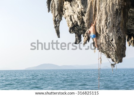 KRABI, THAILAND - Jan 28, 2015 : Rock climbers climbing the wall on Phra Nang beach, One of the most popular rock climbing locations in Krabi, Thailand