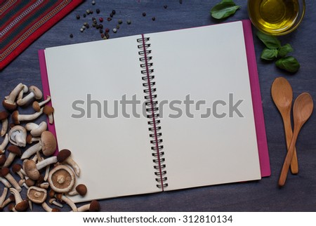 Copy book with mushrooms, condiment, basil and olive oil on dark background