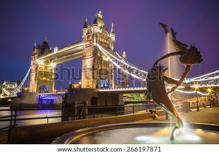The lady and the dolphin fountain with Tower Bridge at night, London, UK