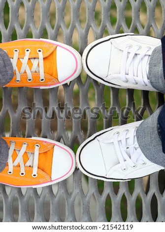 Two couples of teenagers feet in sneakers standing on grid face to face
