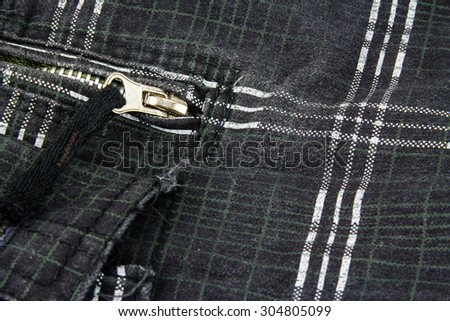 Zipper on black pants with white stripes.