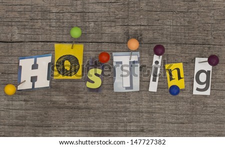 HOSTING  made of letters from newspapers with pins on the wooden background