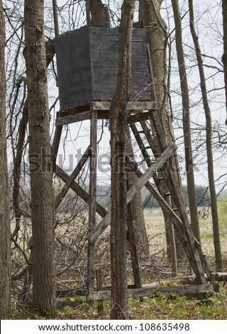 A box type Deer Tower Tree Stand for Hunting in the middle of an oak woods ready for the whitetail deer hunting season with a ladder attached.