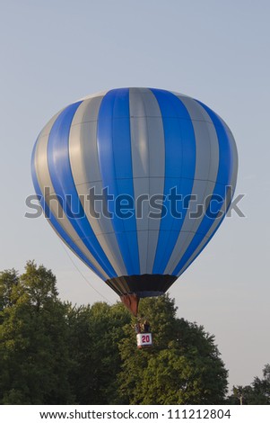 SEYMOUR, WI - AUGUST 3: A Silver and blue striped hot air balloon lifting off at the Balloon Rally at the Annual Hamburger Festival on August 3, 2012 in Seymour, Wisconsin.