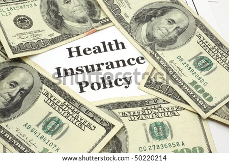 A health insurance policy is surrounded by five one hundred dollar bills signifying the high costs of health care.