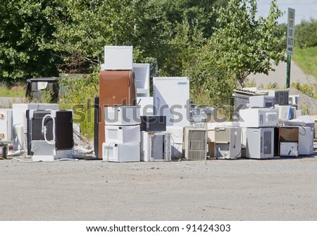 A stack of old appliances such as refrigerators, freezers, and air conditioners stacked up in a pile at a recycling garbage dump.