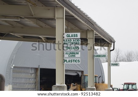 Signs at the recycling center directing where to put glass, lead acid batteries, aluminum cans, plastic, cardboard, tin cans, and paper.