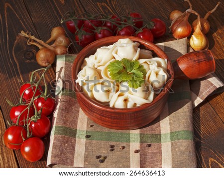 dumplings with meat on a wooden table with tomatoes and onions