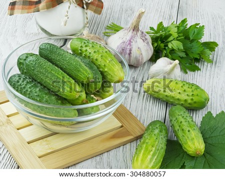 fresh cucumbers on a wooden table with herbs and garlic
