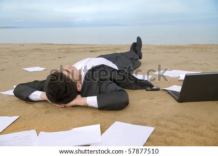 young guy in a business suit is on the beach among the scattered papers