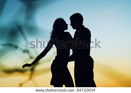 Beautiful couple in love at sunset. Silhouette guys and girls at sunset. They dance.
