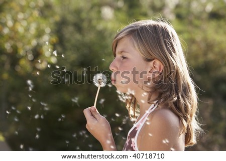 young girl blowing a dandelion and dreaming about the future