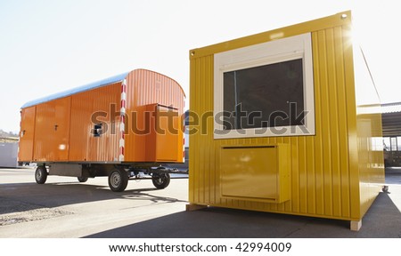 new yellow contractor's shed and orange wagon at industrial yard