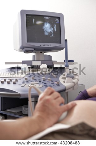 gynecologist making a ultrasound scan of a pregnant woman\'s belly