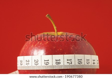 Measuring Tape Wrapped Around a Red Apple as a Symbol of Diet