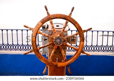 Old Vintage Wooden Helm Wheel near Blue Ovcean