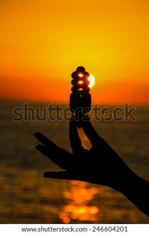 Energy Concept Light Bulb and Sun Setting on the Atlantic Ocean