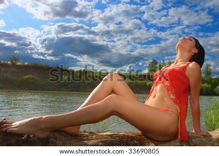 Young smiling beautiful woman in bikini lying on sunny beach