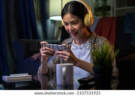 Similar – Image, Stock Photo Teenager girl playing video game at home. Gamer playing online in dark room lit by neon lights. Competition and having fun