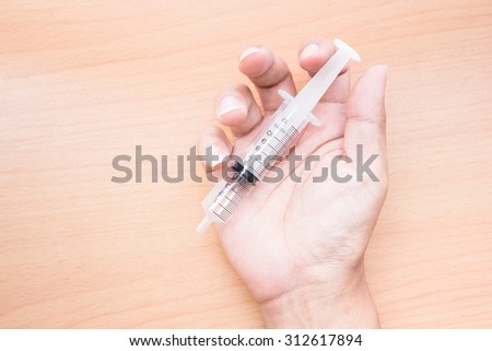 Hand of a doctor with syringe, vintage color tone.