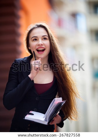 young business woman got an idea. She is holding a notebook and pen on the street