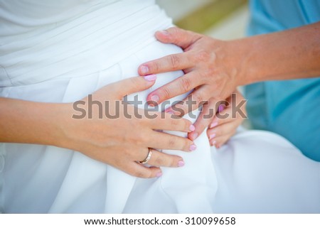 The gentle loving hands of future father and future mother on a stomach of the pregnant woman.