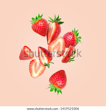 The composition of strawberries on a colored background. Cut strawberries into pieces with copy space. Fresh natural strawberry isolated. Strawberry slices flying in the air