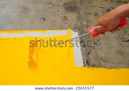 Man Painting a road sign with a paint roller
