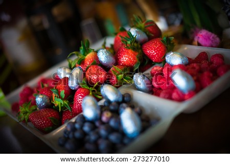 A selection of berries at Easter on a dining table with mini easter eggs dotted about.