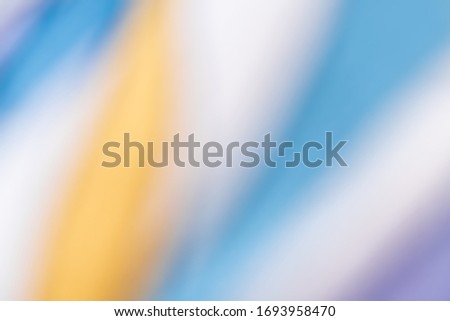 Colorful abstract blurred background. Defocused image of yellow-white-blue textile surface