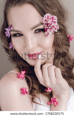 Cosmetics and manicure. Close-up portrait of attractive woman with dry flowers on her face, pastel color, perfect make-up and skin. Fresh, trendy, spring retouched portrait