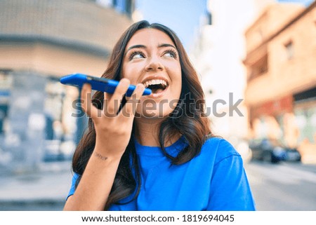 Young hispanic woman smiling happy sending voice message using smartphone at the city.