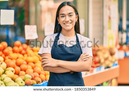 Young latin shopkeeper girl with arms crossed smiling happy at the fruit store. 商業照片 © 