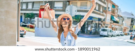 Young beautiful shopper woman smiling happy going to the shops sales holding shopping bags ourtdoors, smiling happy with open arms enjoying the sun