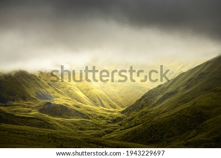 Green summer mountains in misty morning. Clouds over the mountain peaks. Gil-Su valley in North Caucasus, Russia. 