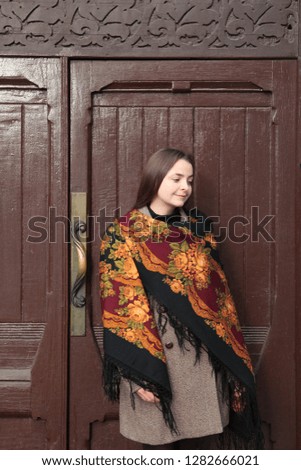 Russian tourist girl in vintage Pavlovo Posad shawl and ancient door of Gustav List House in Glazovsky Lane, 8, Moscow city, Russia. Russian folk style in architecture, fashion. Moscow landmark, sight