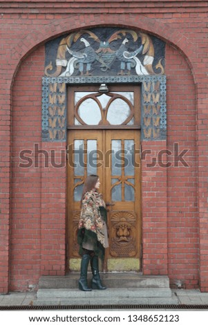 Russian tourist girl in vintage Pavlovo Posad shawl and ancient door of Pertsov's house in Moscow city, Russia. Russian folk style in architecture, fashion. Pertsov's house detail. Moscow landmark