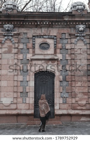 Retro style in architectural fashion. Russian girl in vintage folk Pavlovo Posad shawl with leopard print. Metal door of building in Moscow city, Russia. Architecture of old Moscow. Moscow landmark