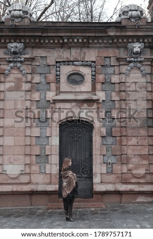 Retro style in architectural fashion. Russian girl in vintage folk Pavlovo Posad shawl with leopard print. Metal door of building in Moscow city, Russia. Architecture of old Moscow. Moscow landmark