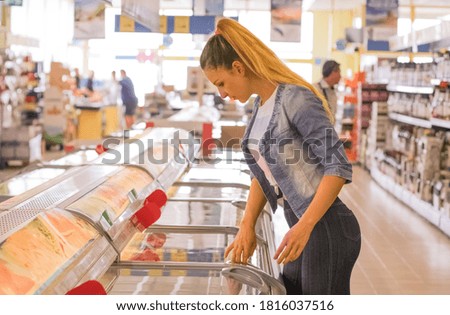 Woman choosing frozen dairy products at supermarket